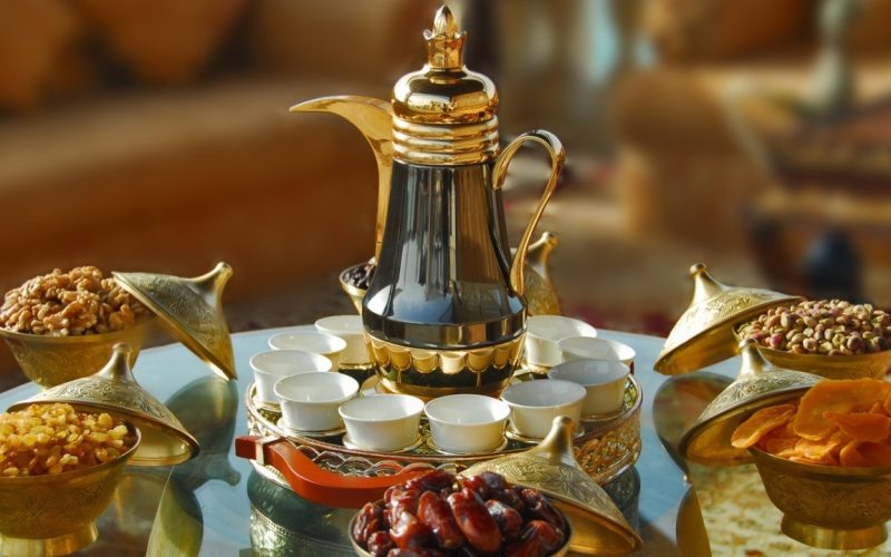 Traditional Arabic coffee set with golden pot, dates, and nuts.