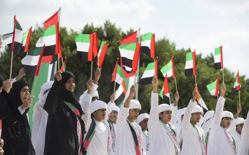 People waving UAE flags at celebration.