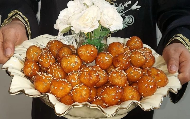 Golden fried loukoumades drizzled with syrup and sesame seeds